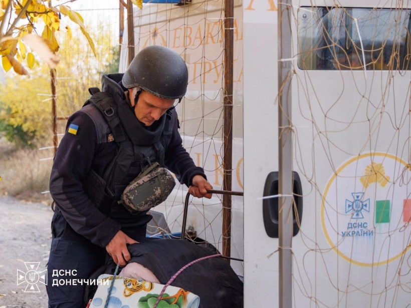 Рятувальник заносить дитячий візок у евакомобіль
