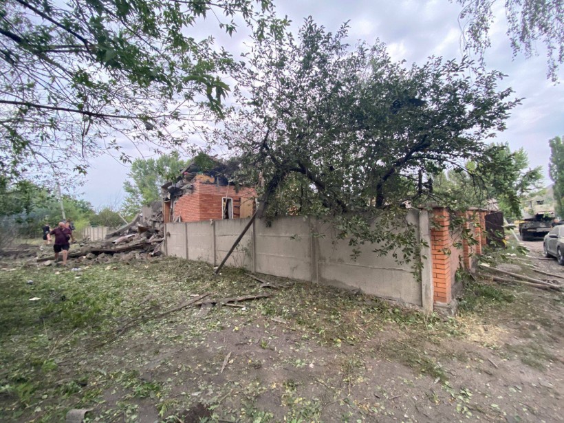 Люди ходять по вулиці біля пошкодженого будинку
