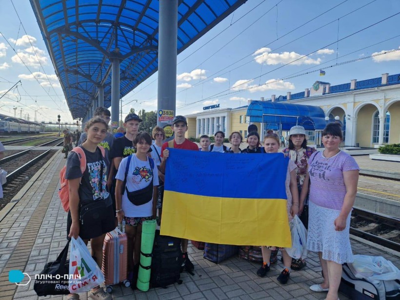 Спільне фото дітей Святогірської громади на пероні залізничного вокзалу. Діти тримають прапор України.