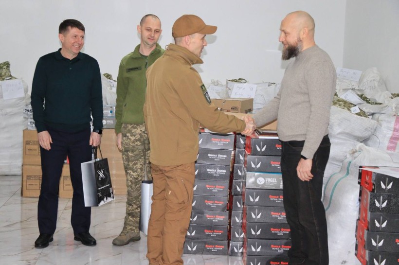 Волонтер та військовий тиснуть один одному руки. Дія при передачі гуманітарної допомоги.