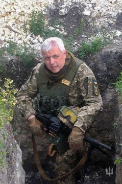 1.
Василь Савін, колишній голова виконкому Макіївки, нині він офіцер 56 окремої мотопіхотної бригади. В бойовому спорядженні з автоматом на колінах. Знаходиться в окопі.