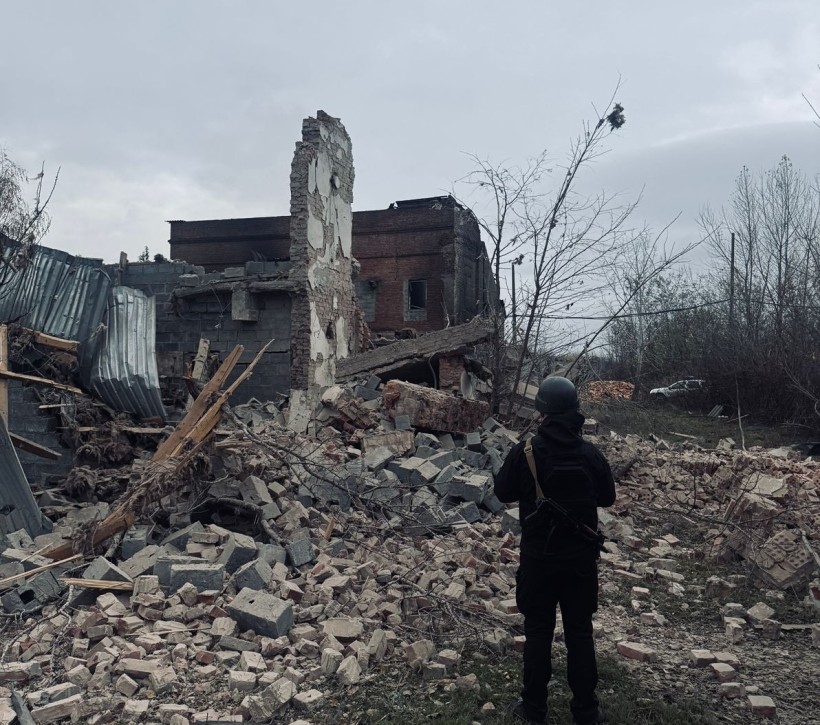 Правоохоронець стоїть біля зруйнованого окупантами будинку