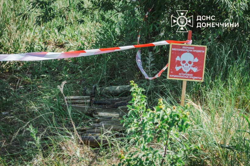 На березі лежать витягнуті з водойми вибухонебезпечні предмети. Місце обтягнуте біло-червоною стрічкою та стоїть табличка про мінну небезпеку.