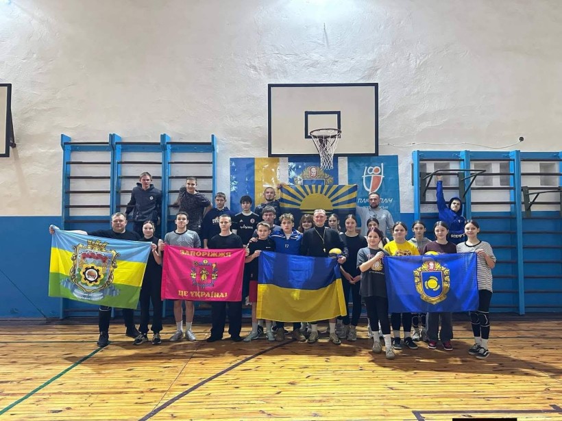 Спільне фото учасників волейбольного турнвру з прапорами громад