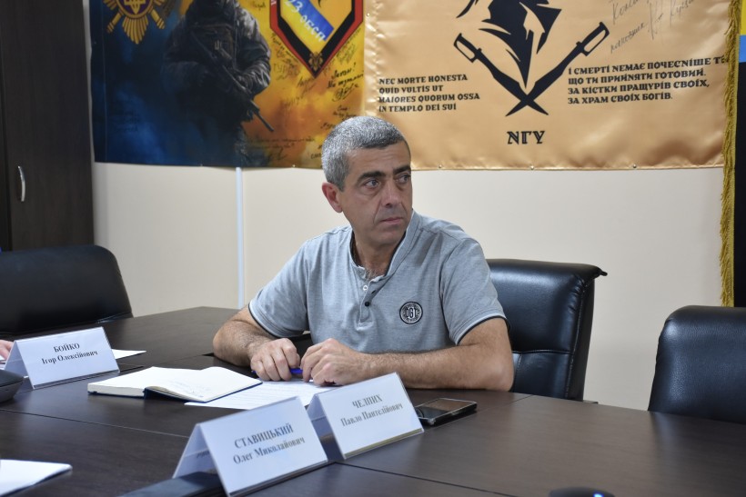 Учасник наради, сидить за столом та уважно слухає доповідь громад.