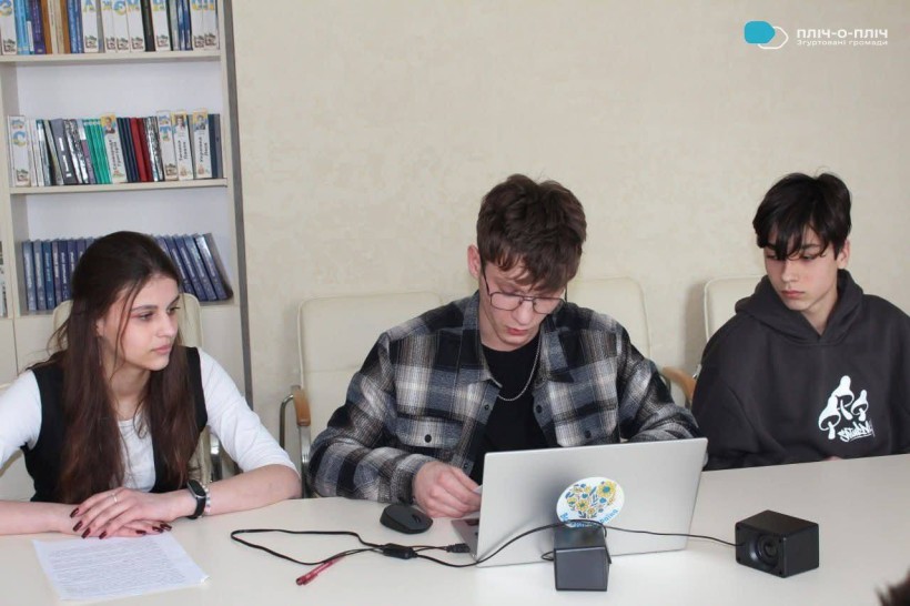 Учні офлайн. Сидять за столом біля ноутбуків.