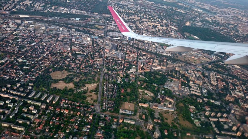 Вид з вікна літака на панораму міста з житловими кварталами і зеленими зонами під ним