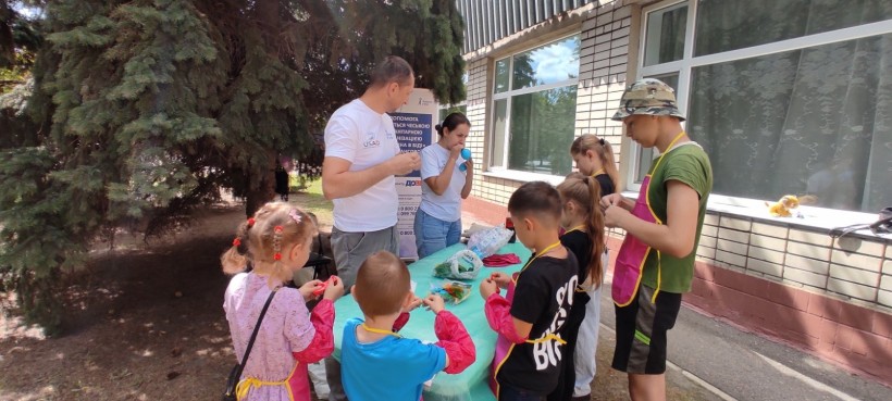 Діти стоять біля столу, психологи розпочинають майстер-клас із виготовлення іграшки-антістресу