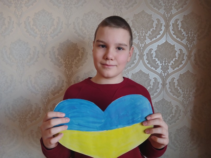 Хлопчик тримає паперове серце жовто-блакитного кольору