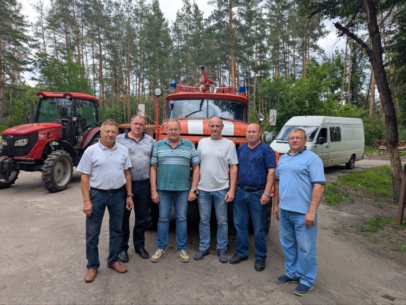 Представники парку "Святі Гори" позують на фоні техніки: пожежного автомобіля, трактора та бусіка