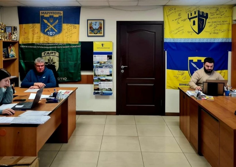 Учасники онлайн наради з питань безбар’єрності. В кабінеті на стінах висять прапори військових бригад.