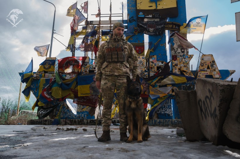 Поліцейський з службовою собакою біля стели Донецької області.