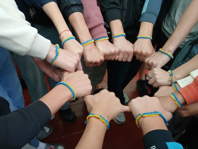 Коло, побудоване з дитячих рук, на яких одягнені синьо-жовті саморобні браслети