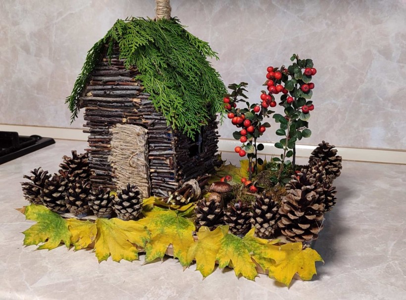 Маленький будинок із гілочок, шишок, калини і листя