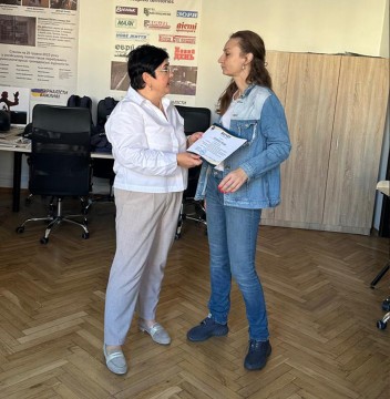 Наталія Адамова вручає Юлії Паніній ваучери на проходження навчання