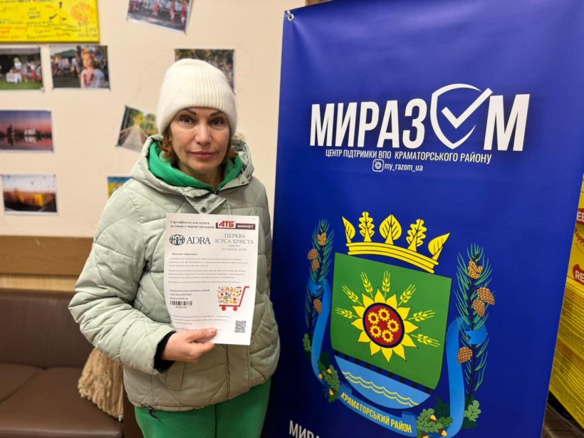 Жінка тримає у руках флаєр про гуманітарну допомогу та організації, які ії надають.