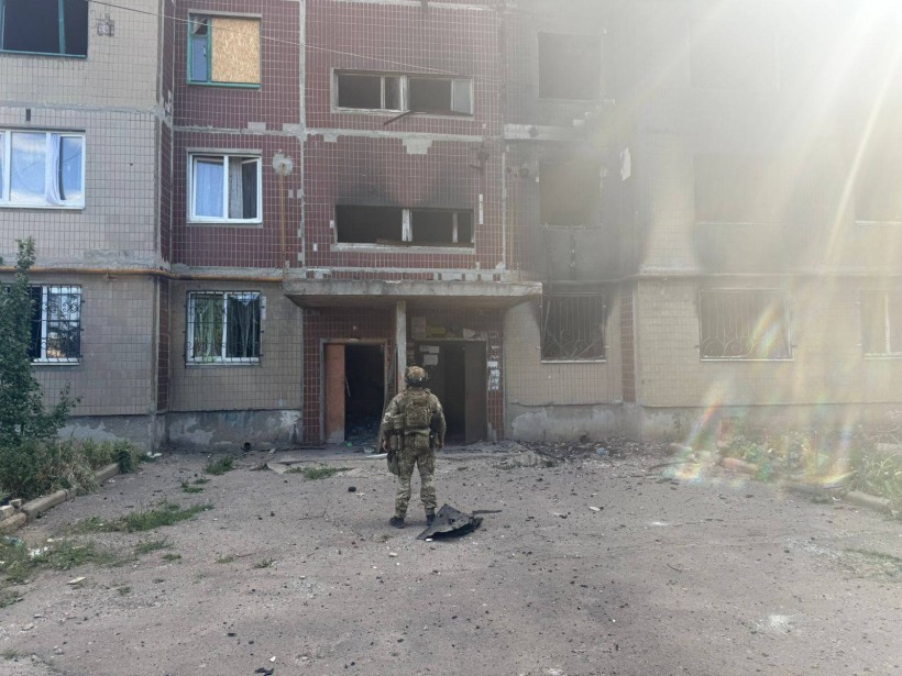 Пошкоджений будинок після ворожого обстрілу та правоохоронець поруч