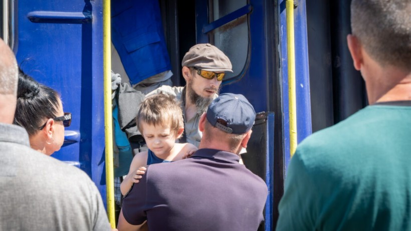 Волонтери допомагають маленьуій дитині вийти з евакуаційного потяга