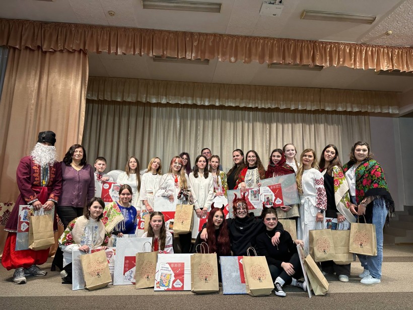 Спільне фото дітей на сцені. Хлопці та дівчата тримають подарунки.