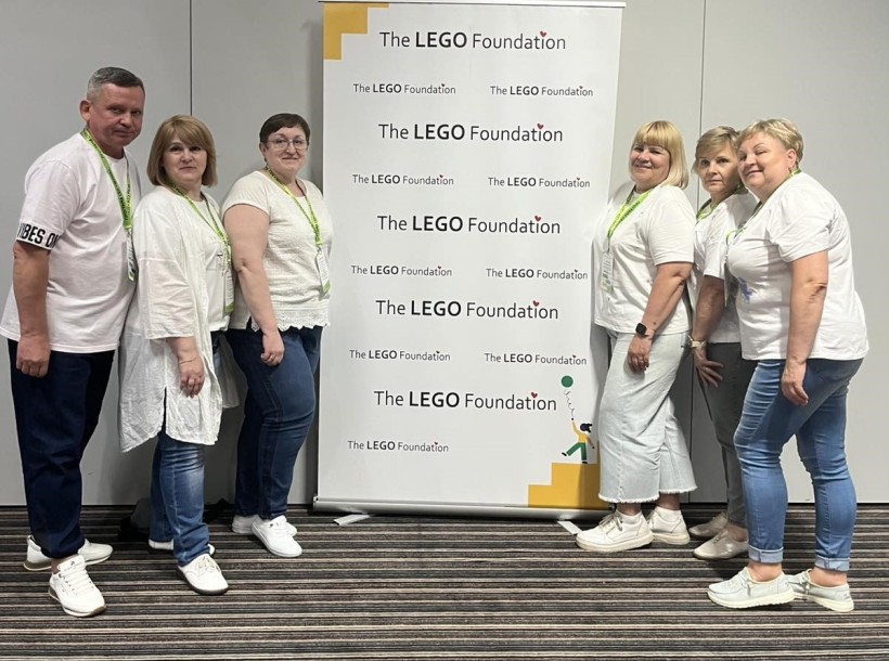 Учасники освітньої панельної дискусії LEGO Foundation з Донеччини біля банеру з логотипом тренінгу