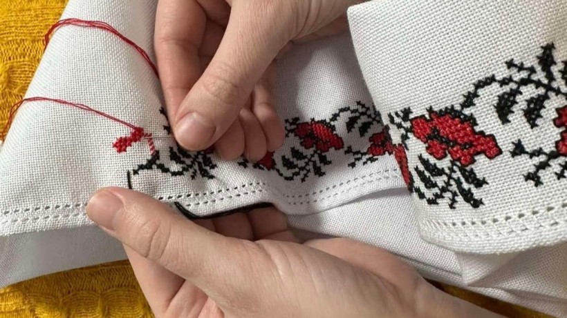 Руки майстрині вишивають сорочку
