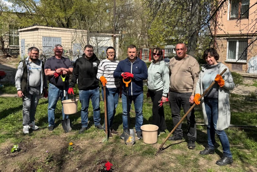 Учасники акції стоять з садовим інвентарем та висаджують квіти.