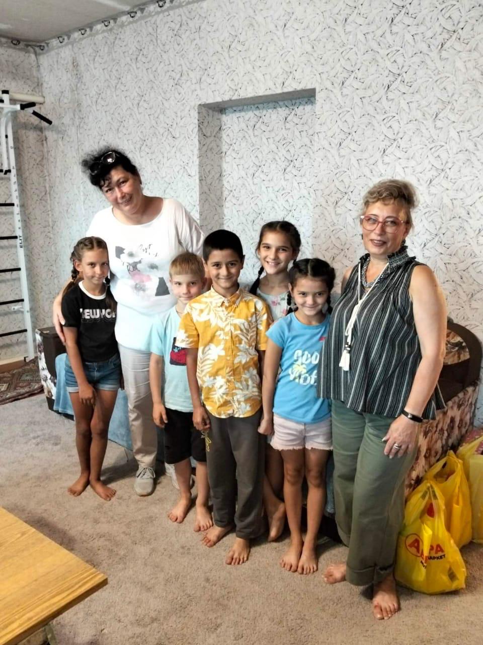 Родина разом з представниками адміністрації, спільне фото. Всі стоять у кімнаті, діти посміхаються.