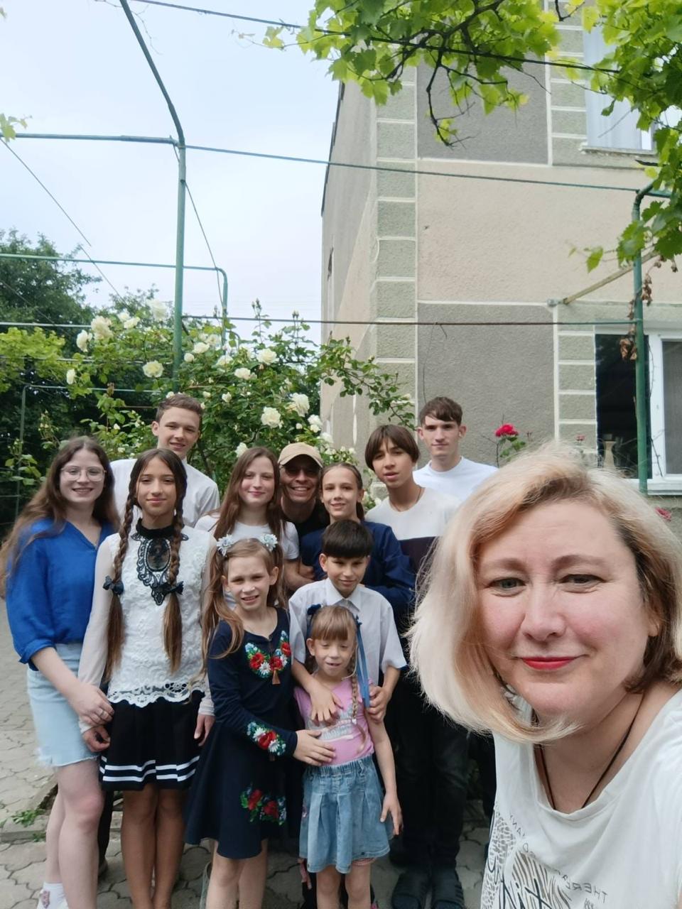 Представники служби у справах облдержадміністрації відвідували дітей, які виховуються в дитячих будинках сімейного типу. Хлопці та дівчата стоять біля воріт позаду них будинок.
