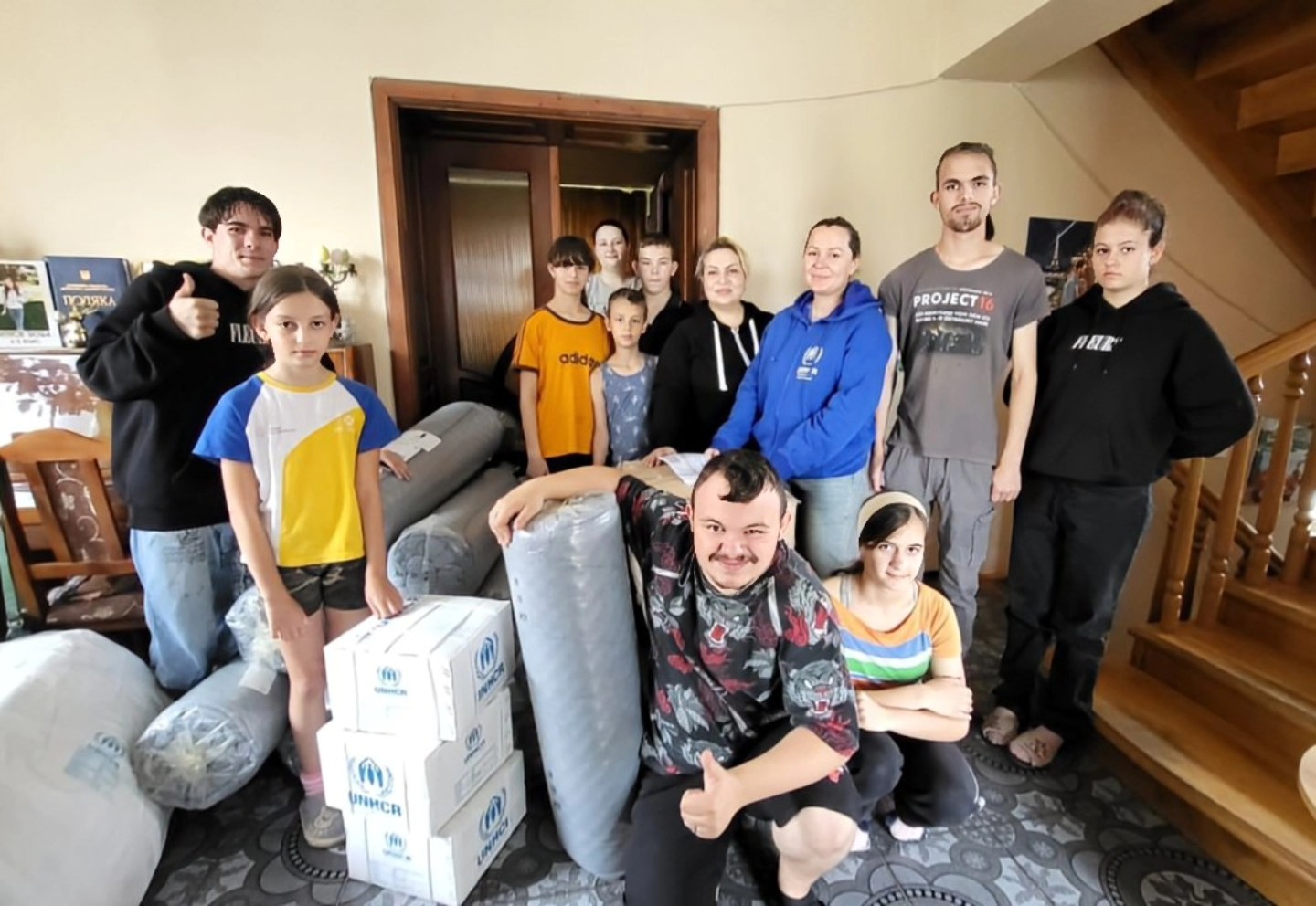 Дитячий будинок сімейного типу Олени Мехедько отримав гуманітарну допомогу. Вихованці стоять поруч з ковдрами, матрацами, подушками, наборами постільної білизни, посуду тощо.
