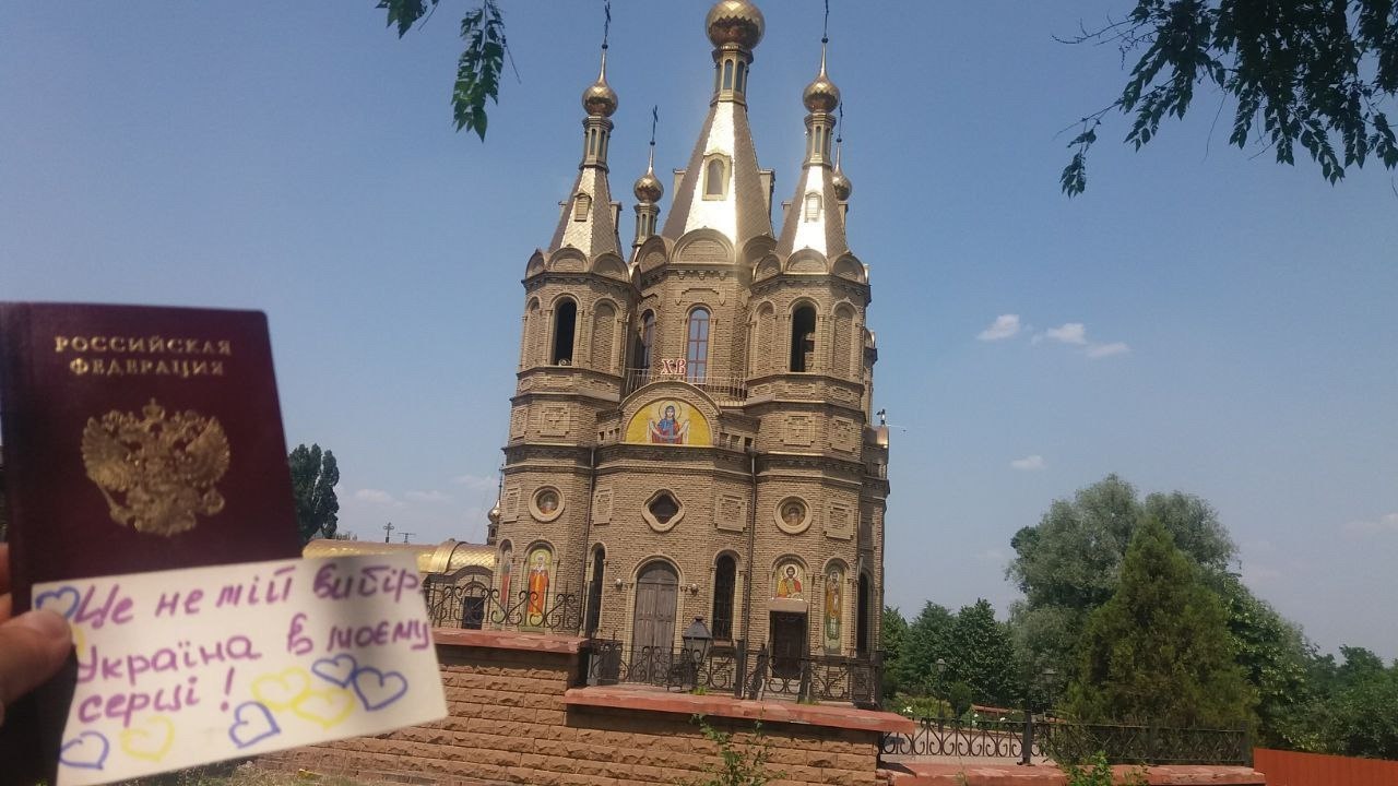На фоні храму російський паспорт з запискою українсьою мовою, на якій намальовані серця .
