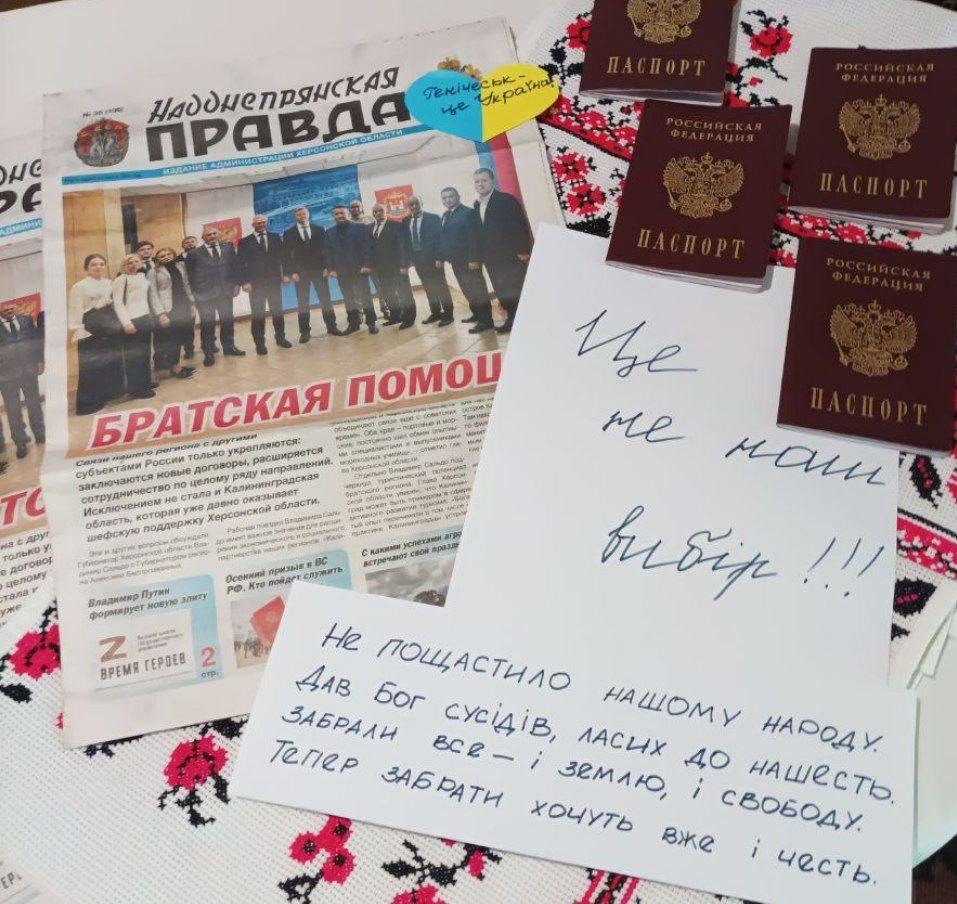 Російські паспорти лежат ьна фоні російських газет. Поряд записки в підтримку України.