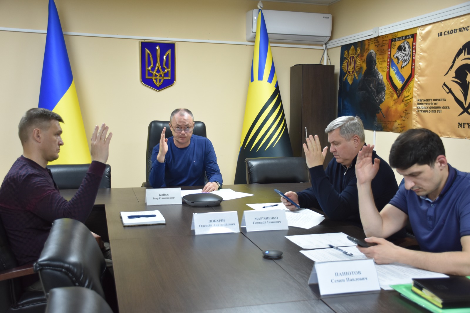 Засідання комісіє за столом в групі чотирьох чоловіків проводить голосування