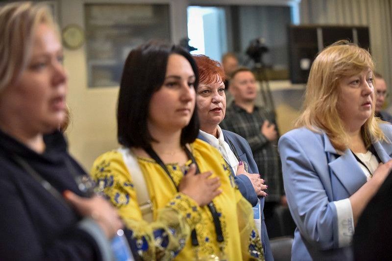 Учасники STEM-форуму з рукою на серці під час виконання гімну України