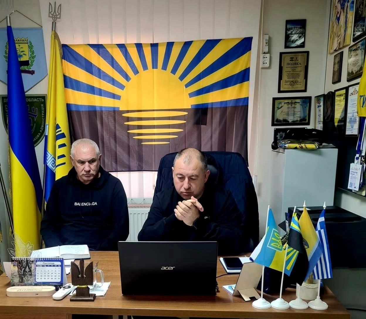 Начальник Сартанської селищної військової адміністрації Олександр Куркчи  та  заступник начальника управління - начальник відділу містобудування управління містобудування та архітектури Донецької облдержадміністрації Іван Оліфіровський.
Сидять біля монітора та обговорюють питання про розуміння безбар’єрності. Позаду них прапор Донеччини.