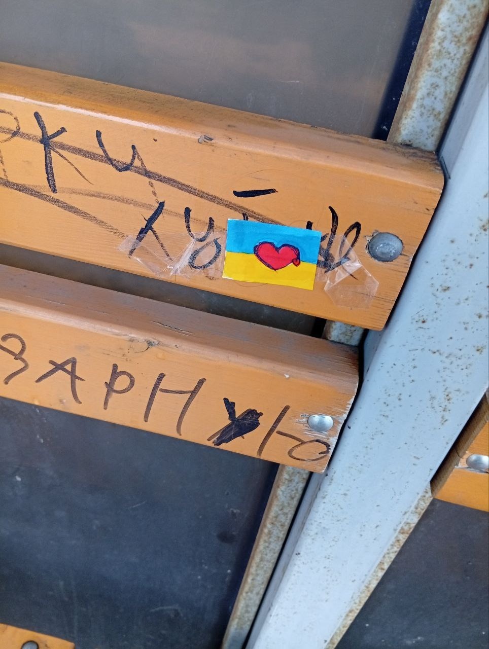 Червоне серце на жовто -блакитному фоні наклеєне на дерев'яній скамійці в окупованому місті Донецької області.