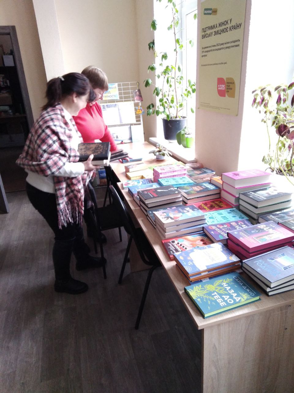 Дві жінки розглядають на столі книги для Бахмутської громади від видаництва Vivat