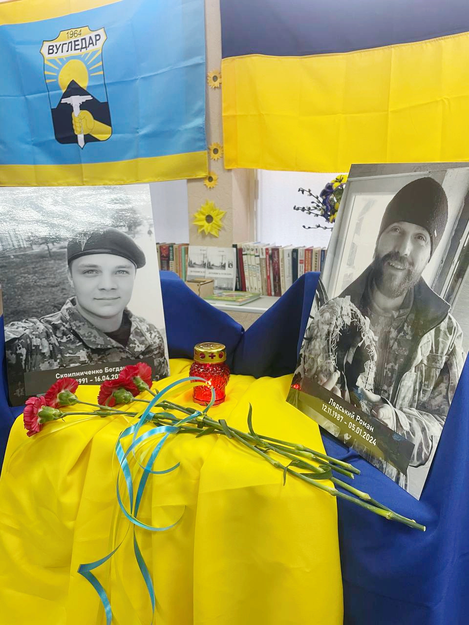 Фото загиблих захисників на фоні прапорів Вугледарської громади та України