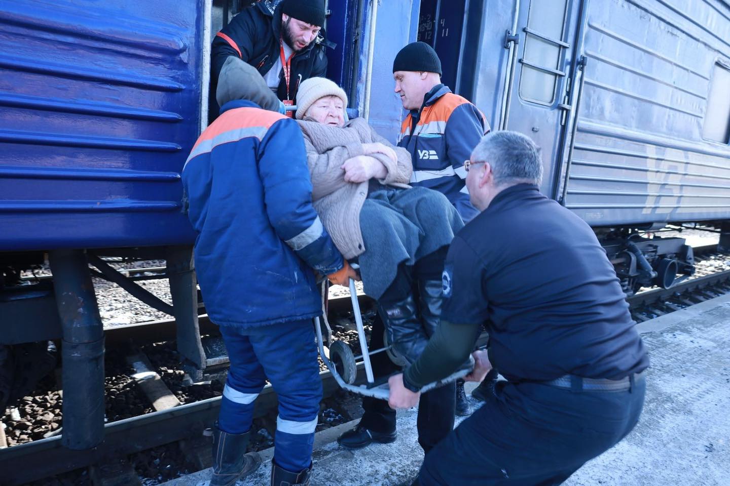 Представники ДСНС та волонтери допомагають жінці в кріслі колісному завантажитись до евакуаційного потяга