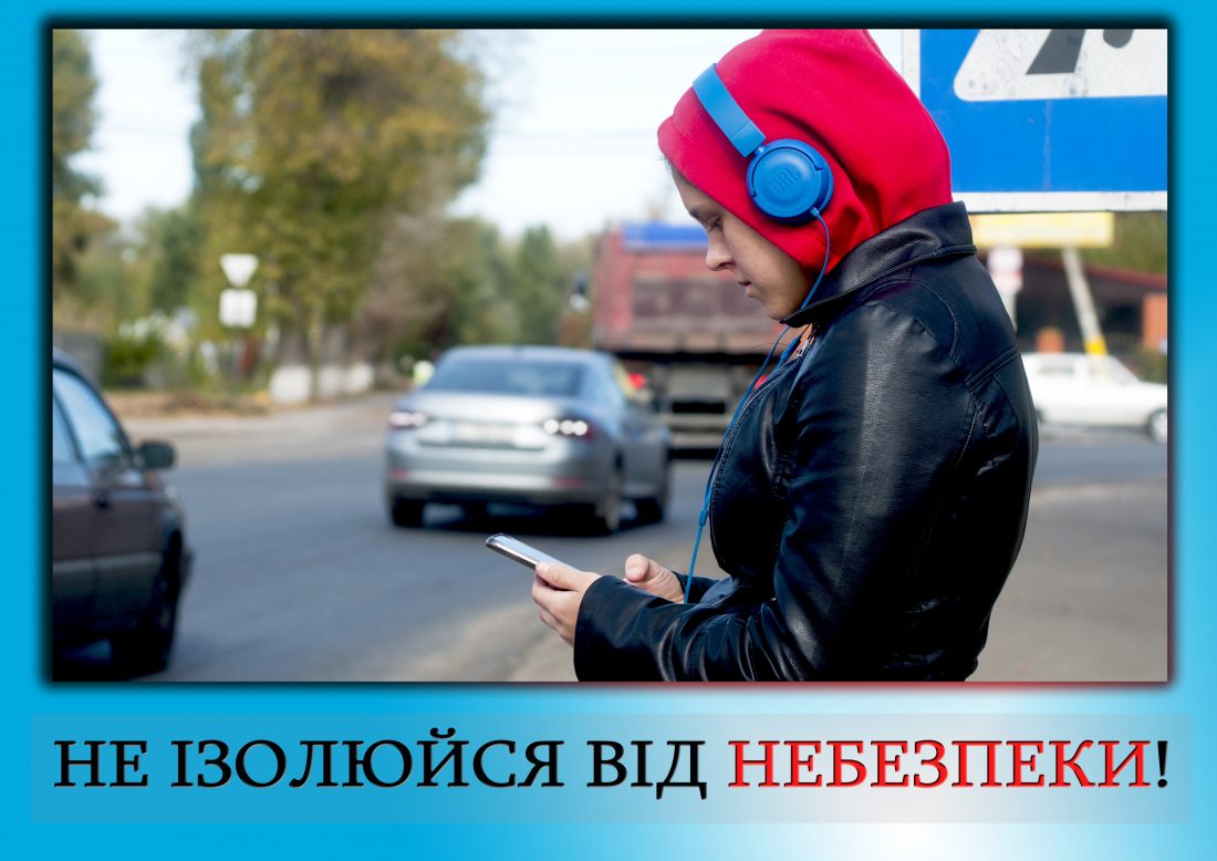 Дитина в навушника, капюшоні та з телефоном в руці збирається перейти дорогу