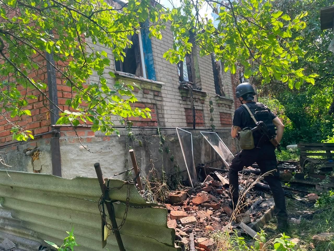 Правоохоронець стоїть біля зруйнованого обстрілом будинку