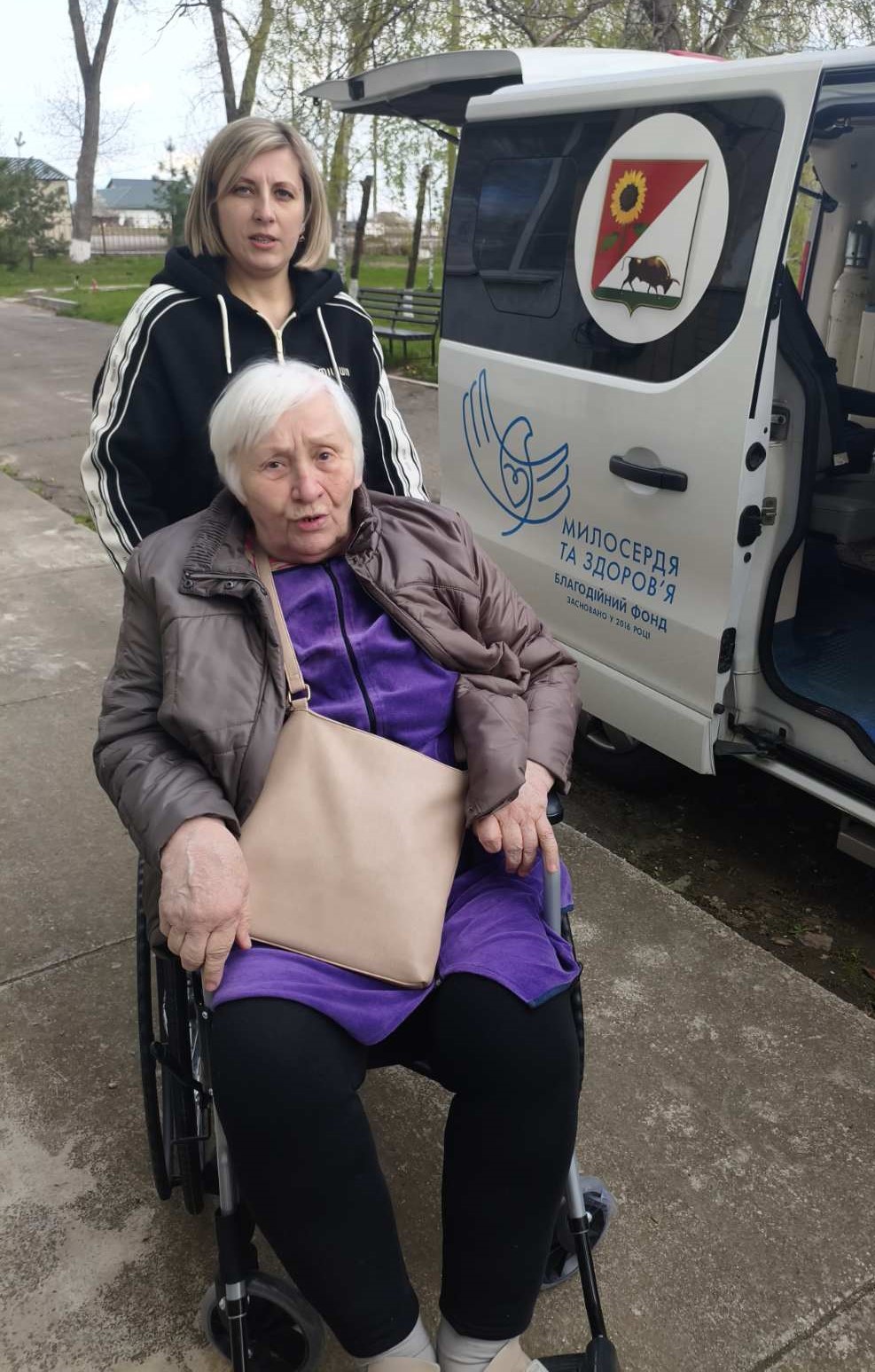 Людина в кріслі колісному у супроводі соціальної працівниці