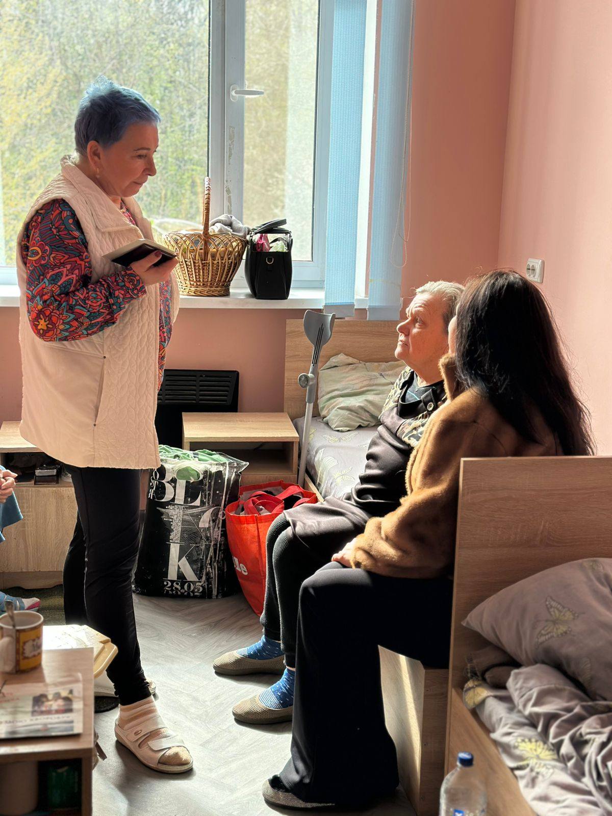 З жінкою старшого віку спілкуються працівниці Будинку ветеранів