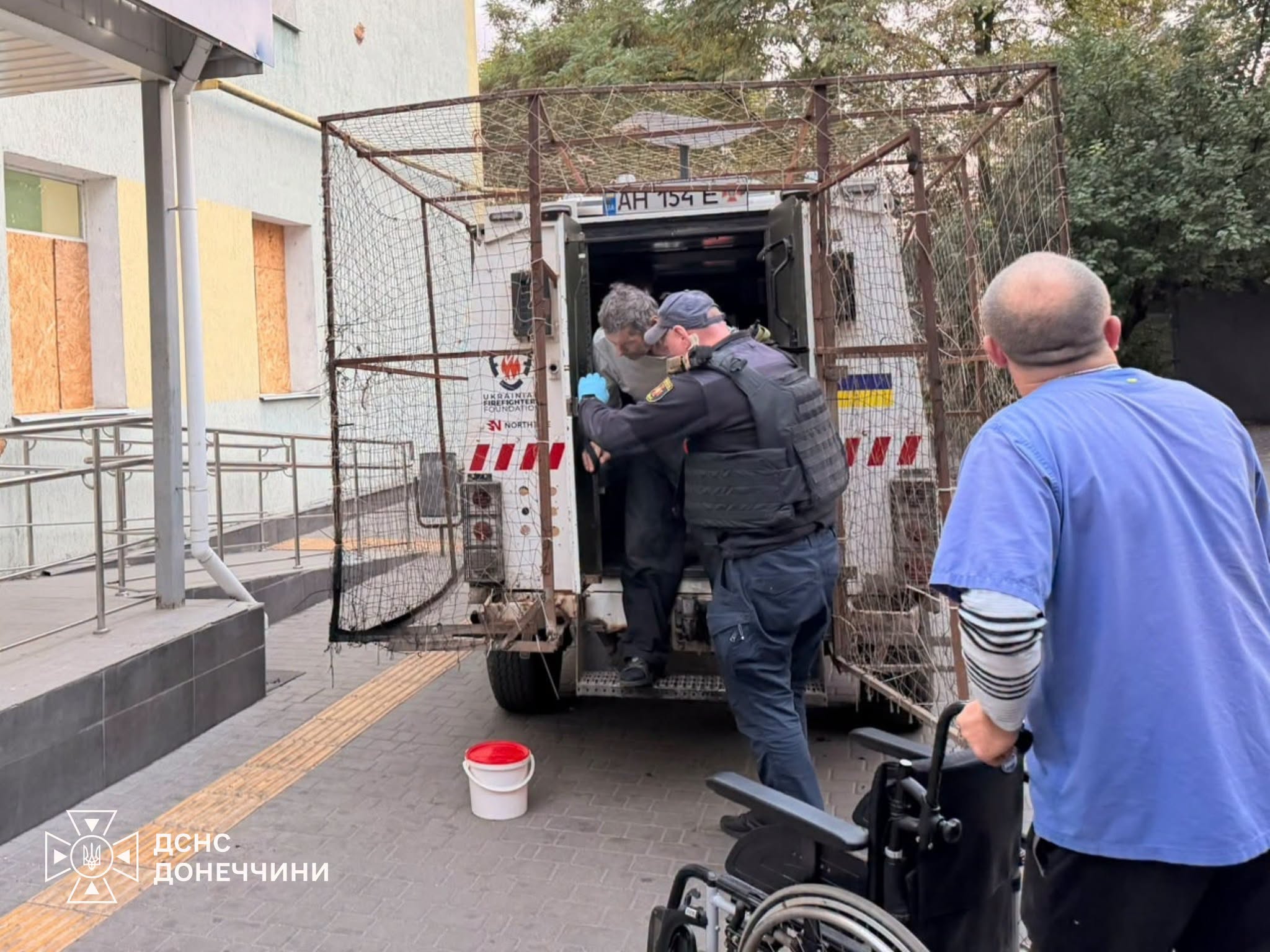 Рятувальники групи "Фенікс" допомагають людям сісти до евакомобіля