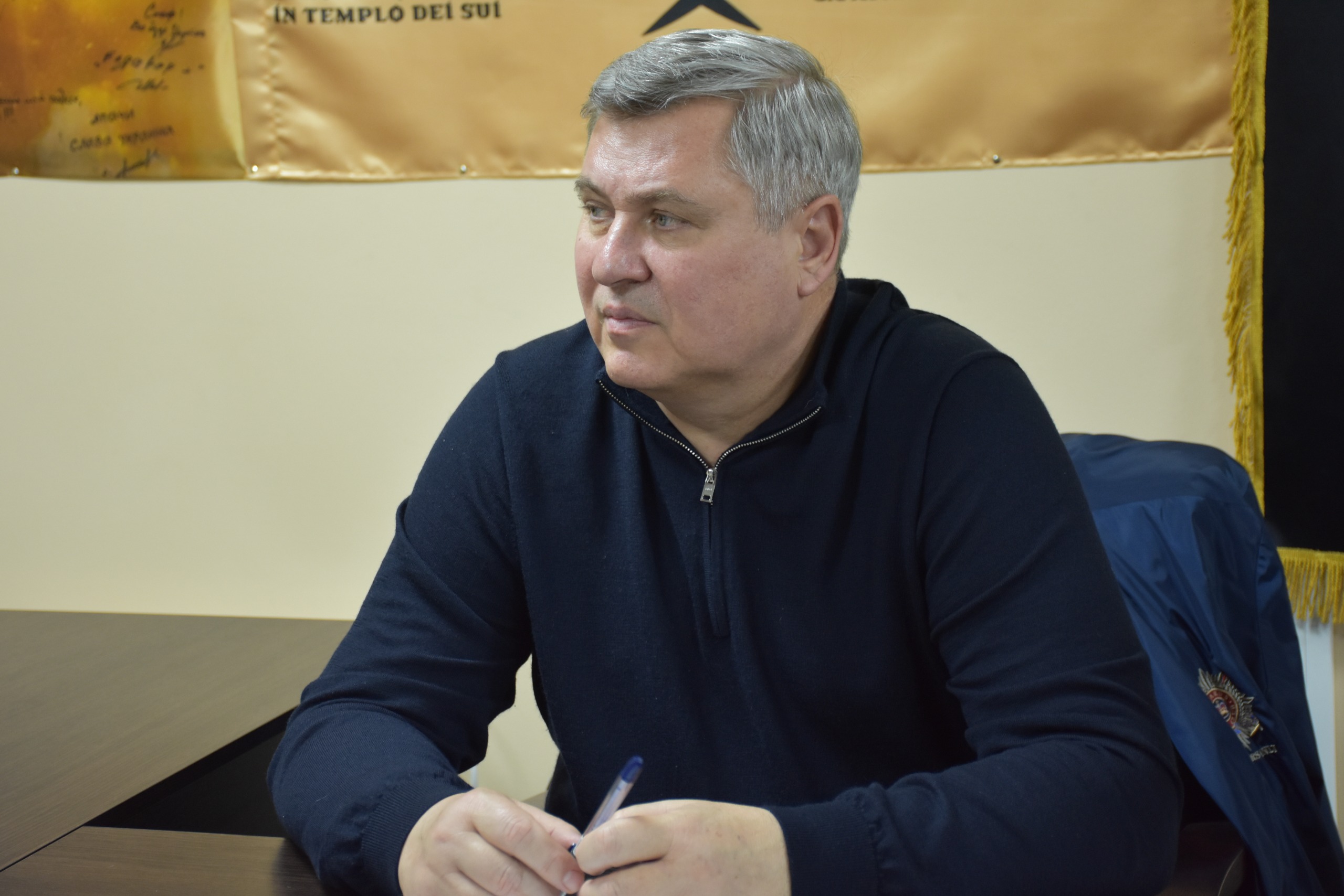 Чоловік сидить за столом та тримає в руках ручку