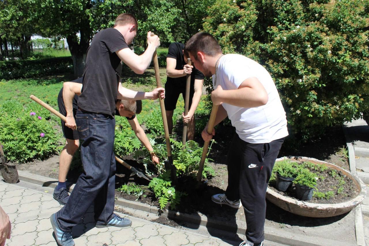 Група підлітків з лопатами облаштовує клумбу